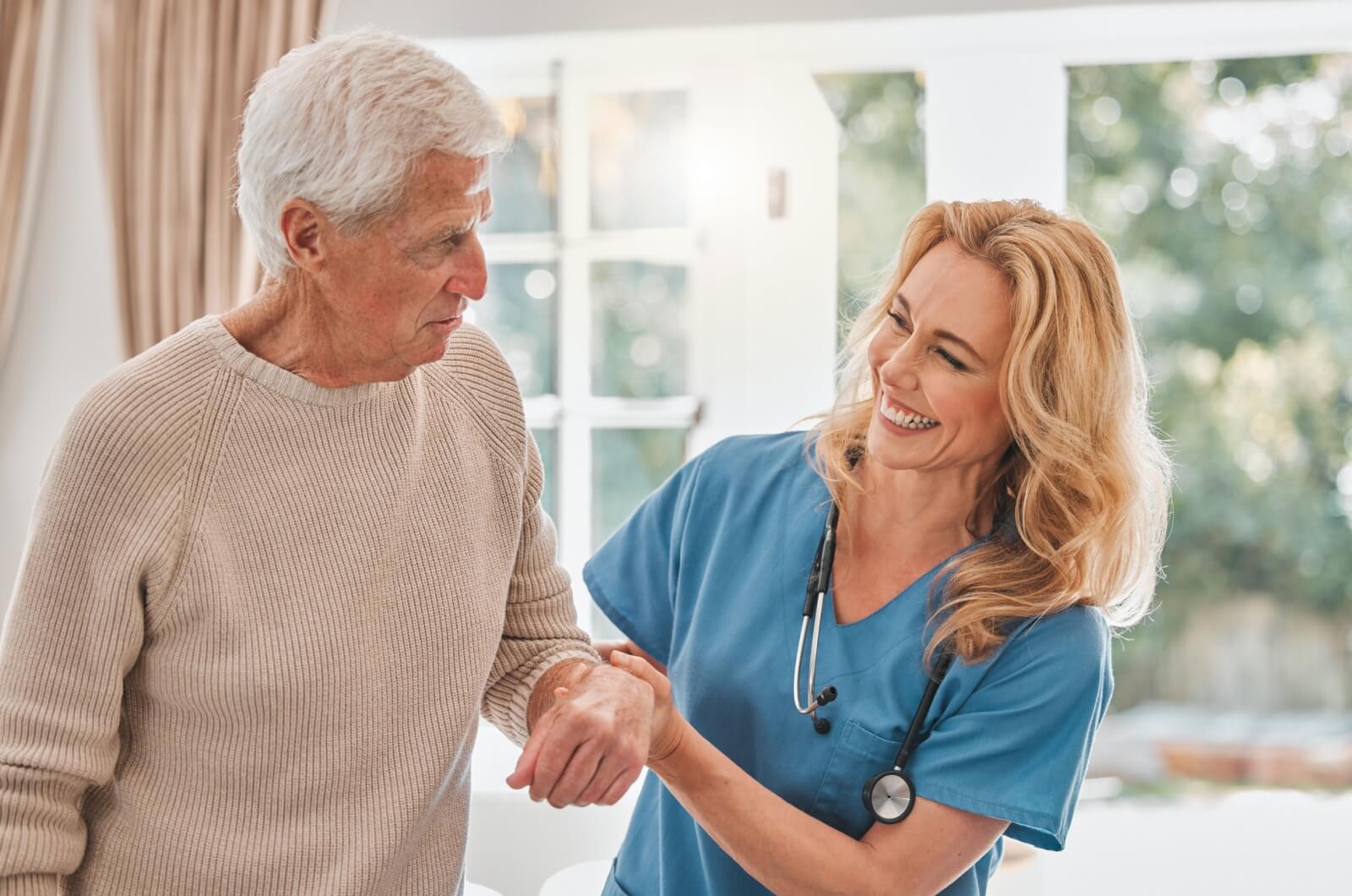 A smiling staff member in assisted living helping an older adult.