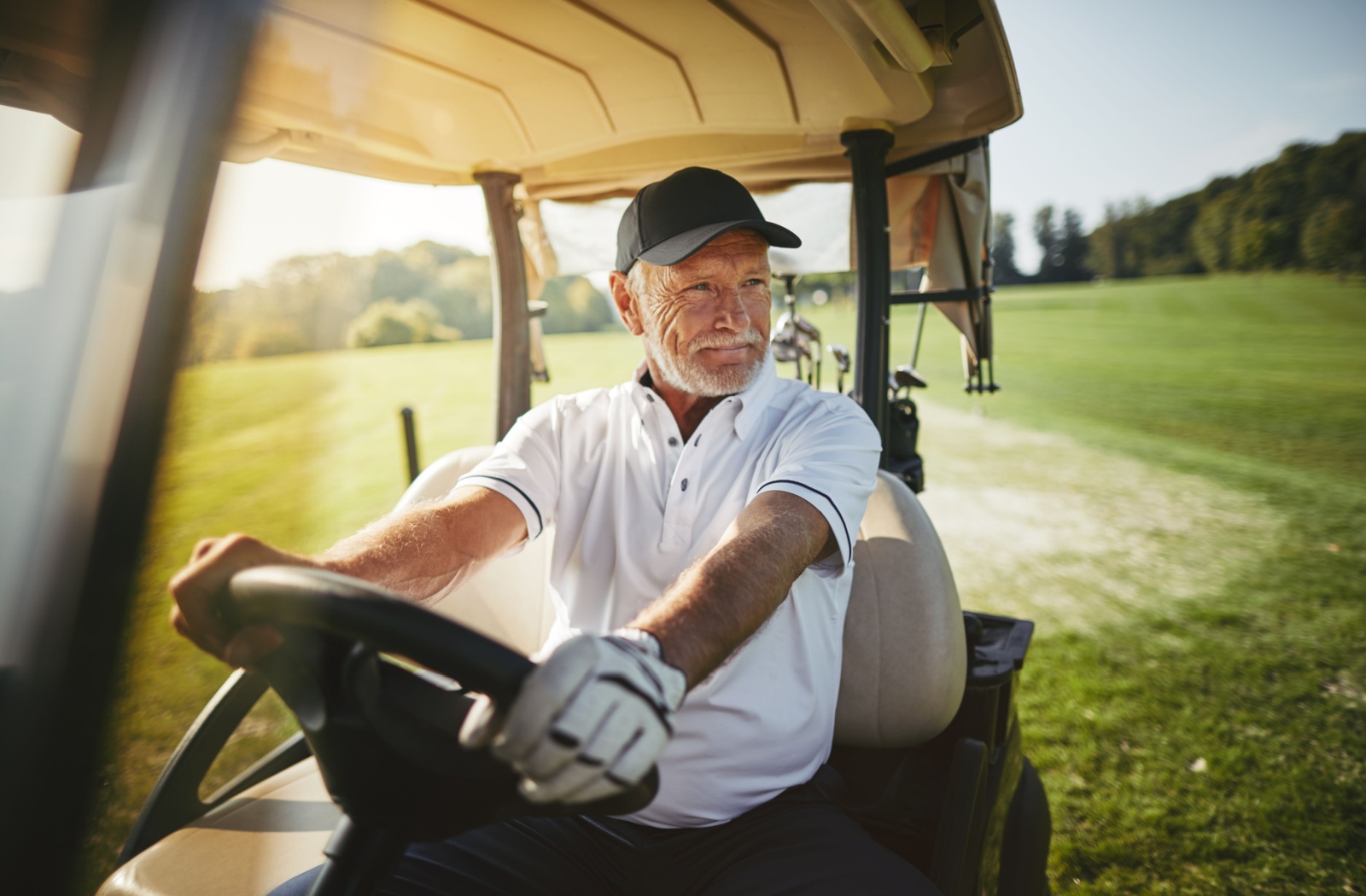 A senior drives a golf cart on a sunny summer afternoon