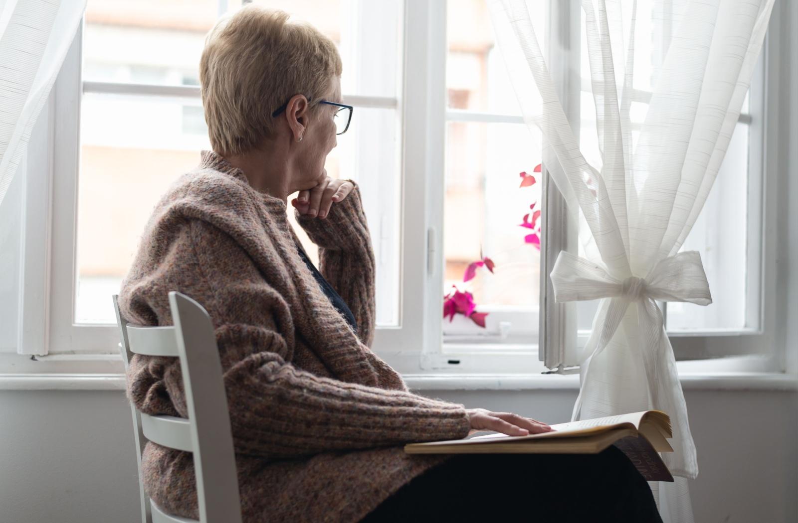 senior woman looks out a window